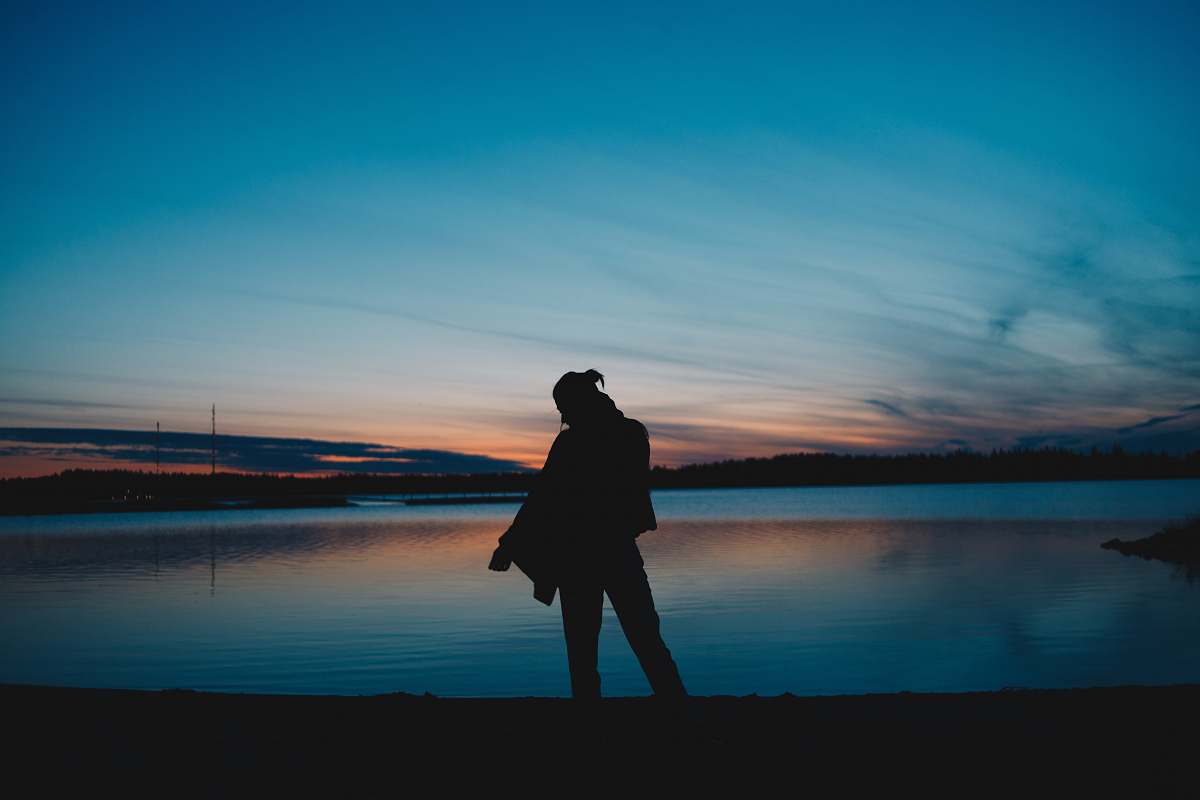 person silhouette photography of unknown standing near body of water human