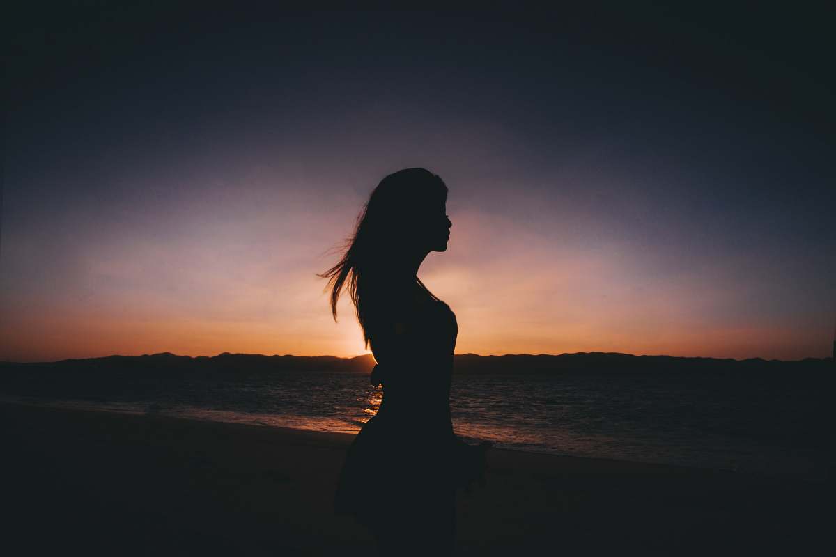 human silhouette photography of woman standing near seashore person
