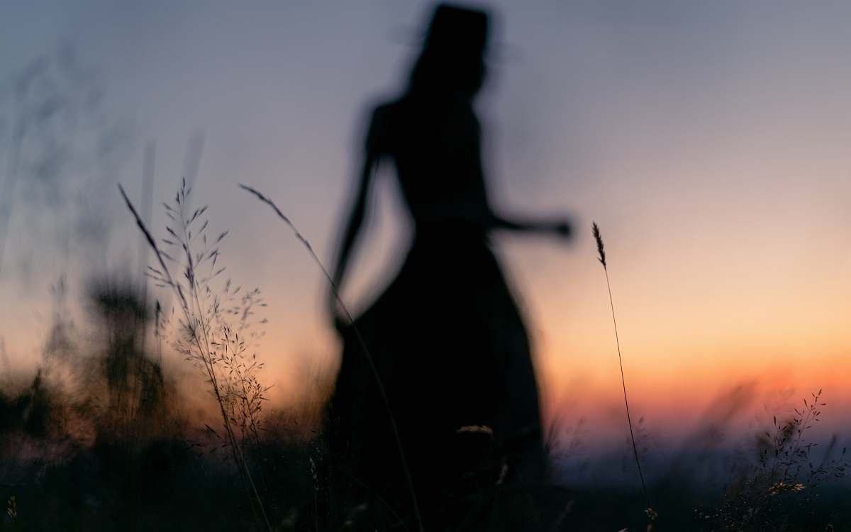 grass silhouette photography of woman standing on grass field plant
