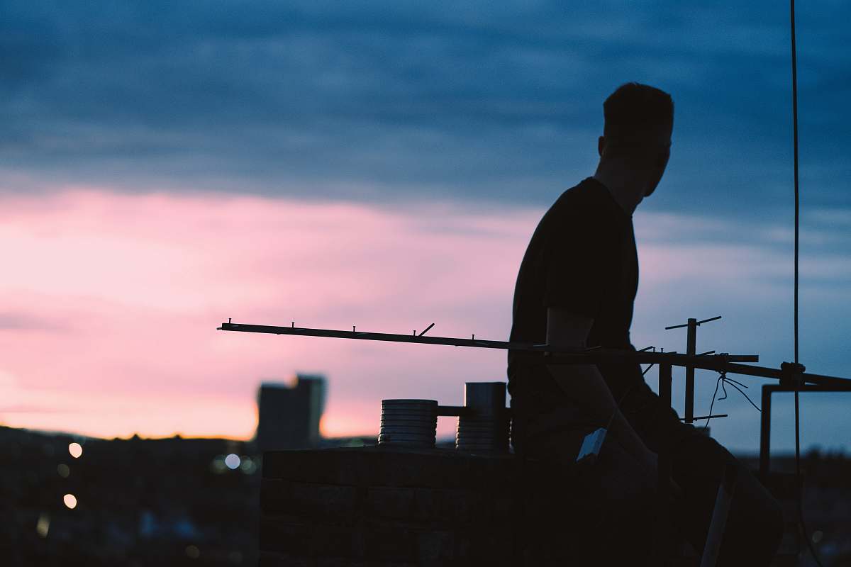 human silhouette view of man sits on higher ground outdoors