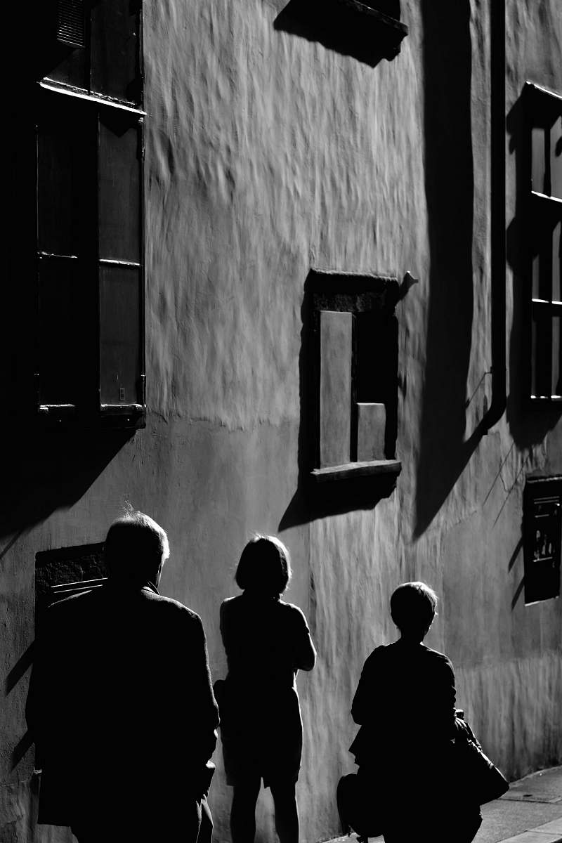 human three persons walking near gray wall black-and-white
