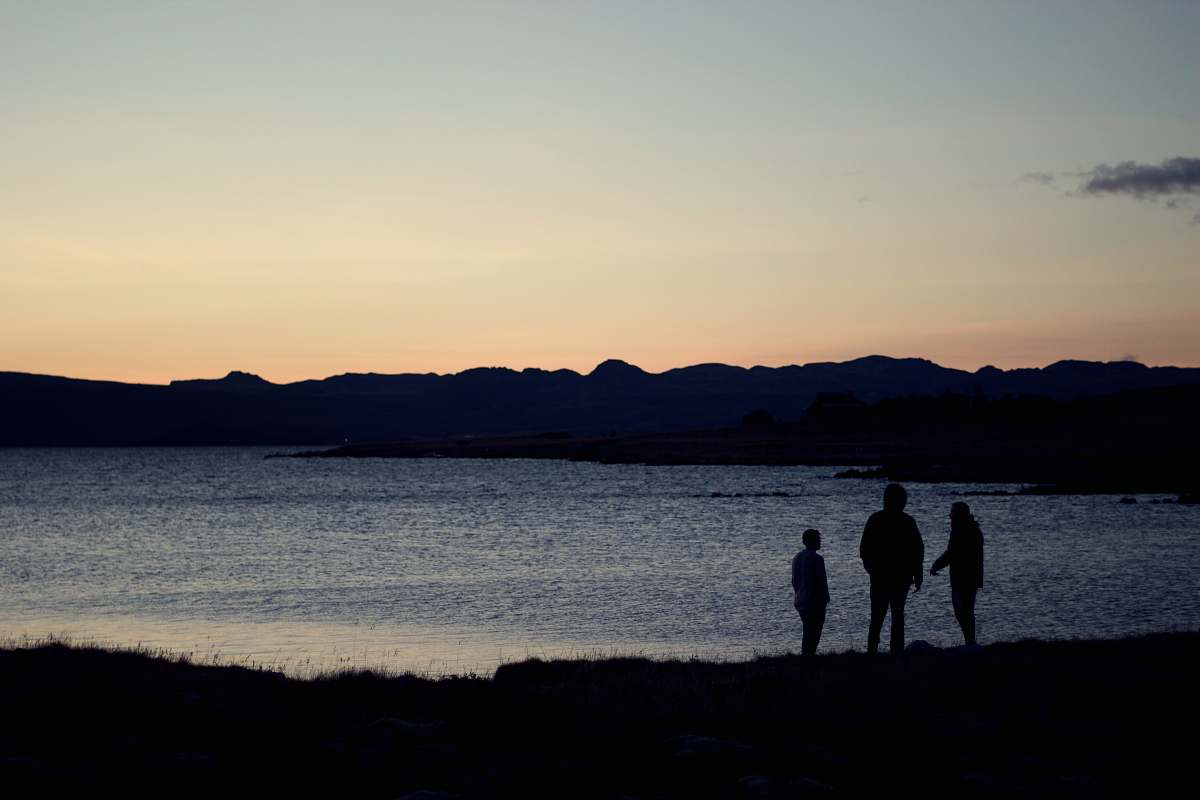dawn three silhouette of person standing beside body of water dusk