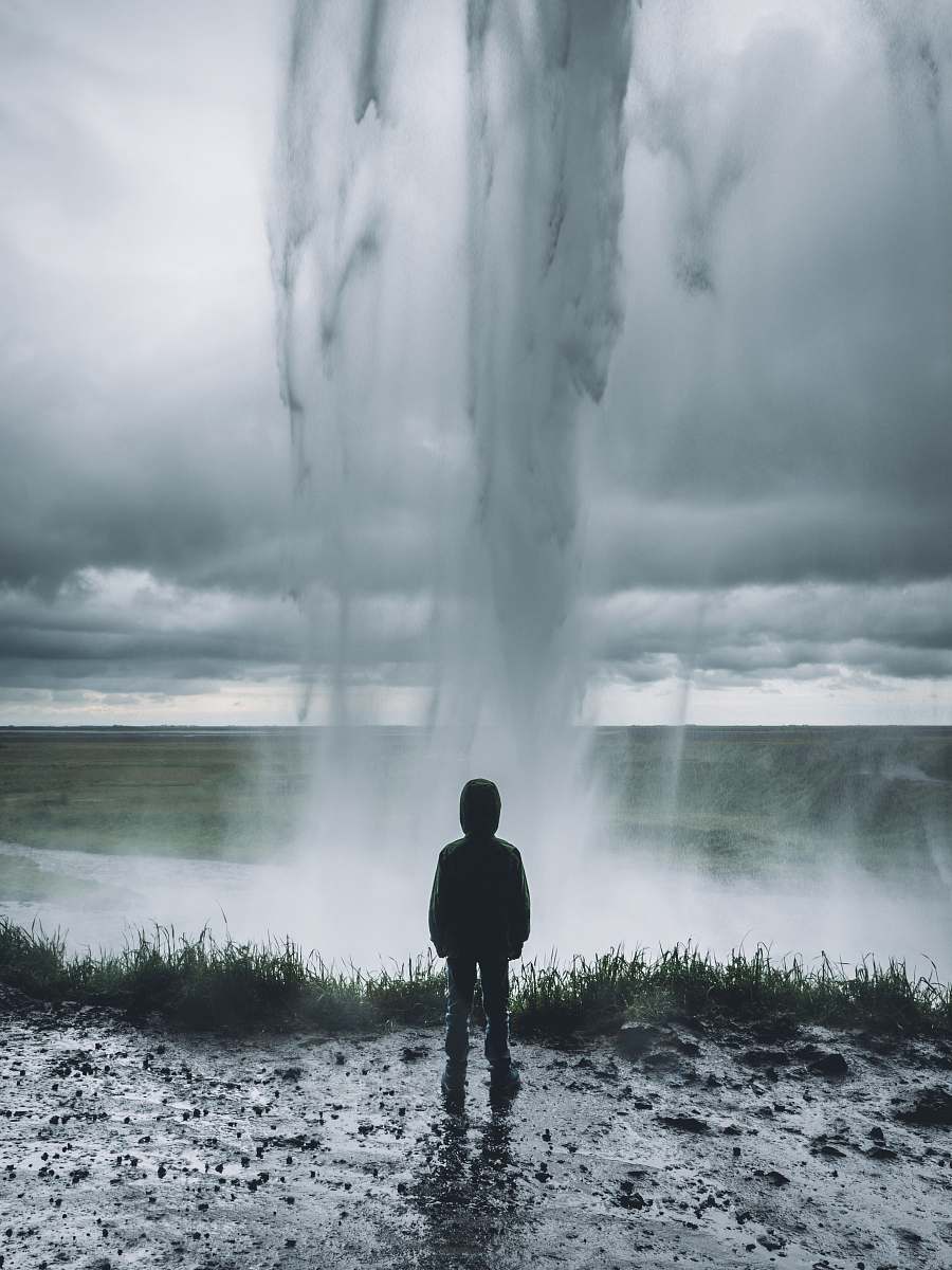 iceland toddler standing in front of water formation grey