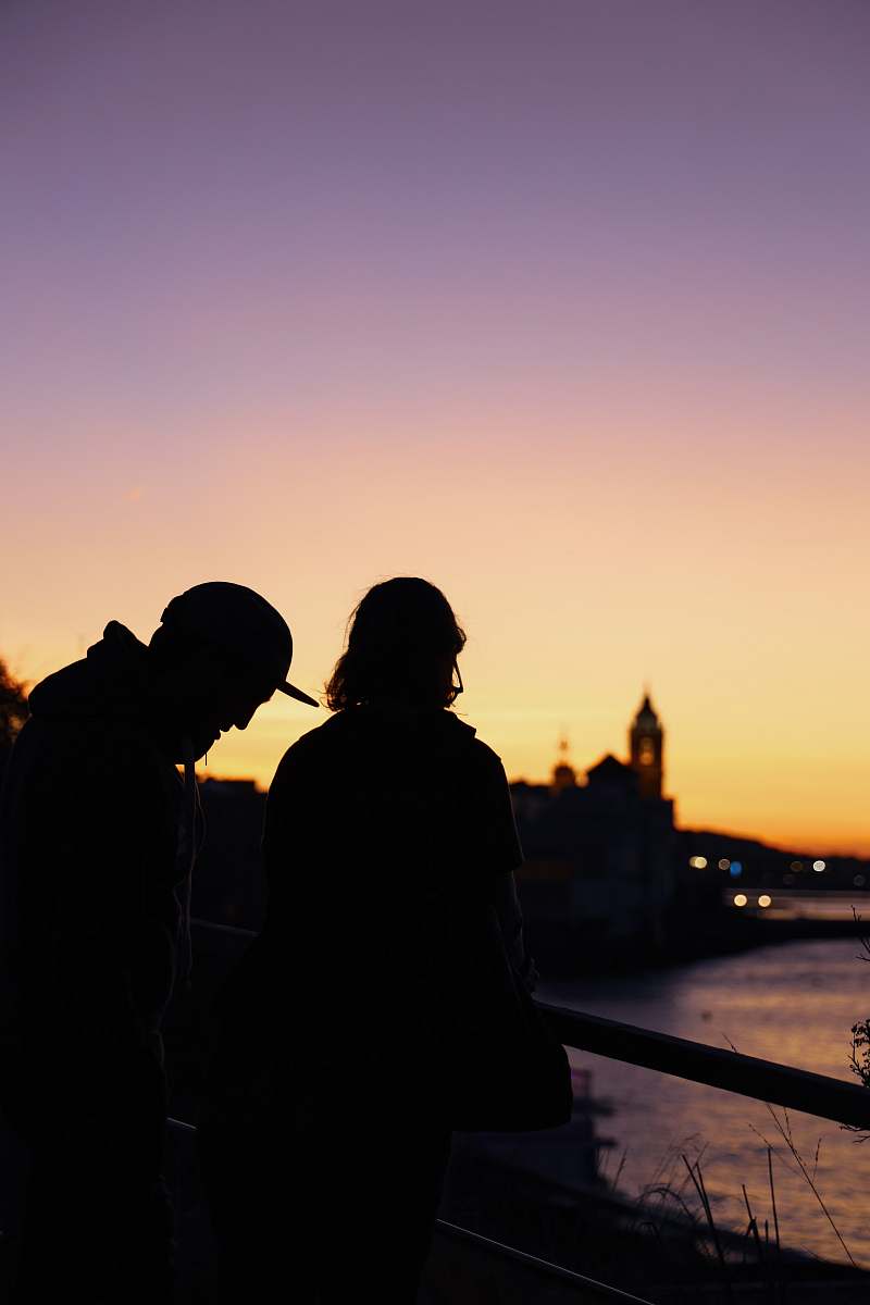 human two people standing near railings viewing body of water railing