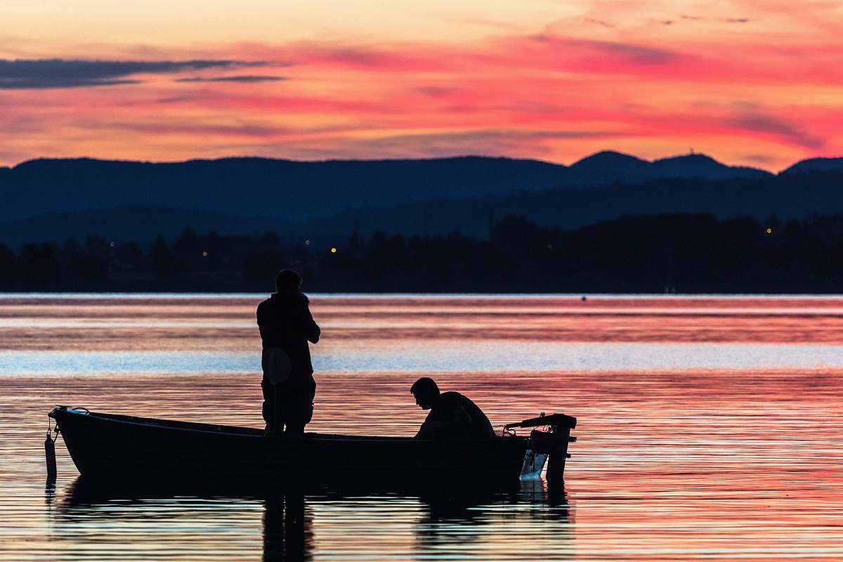 person two person standing on boat on body of water during golden hour people