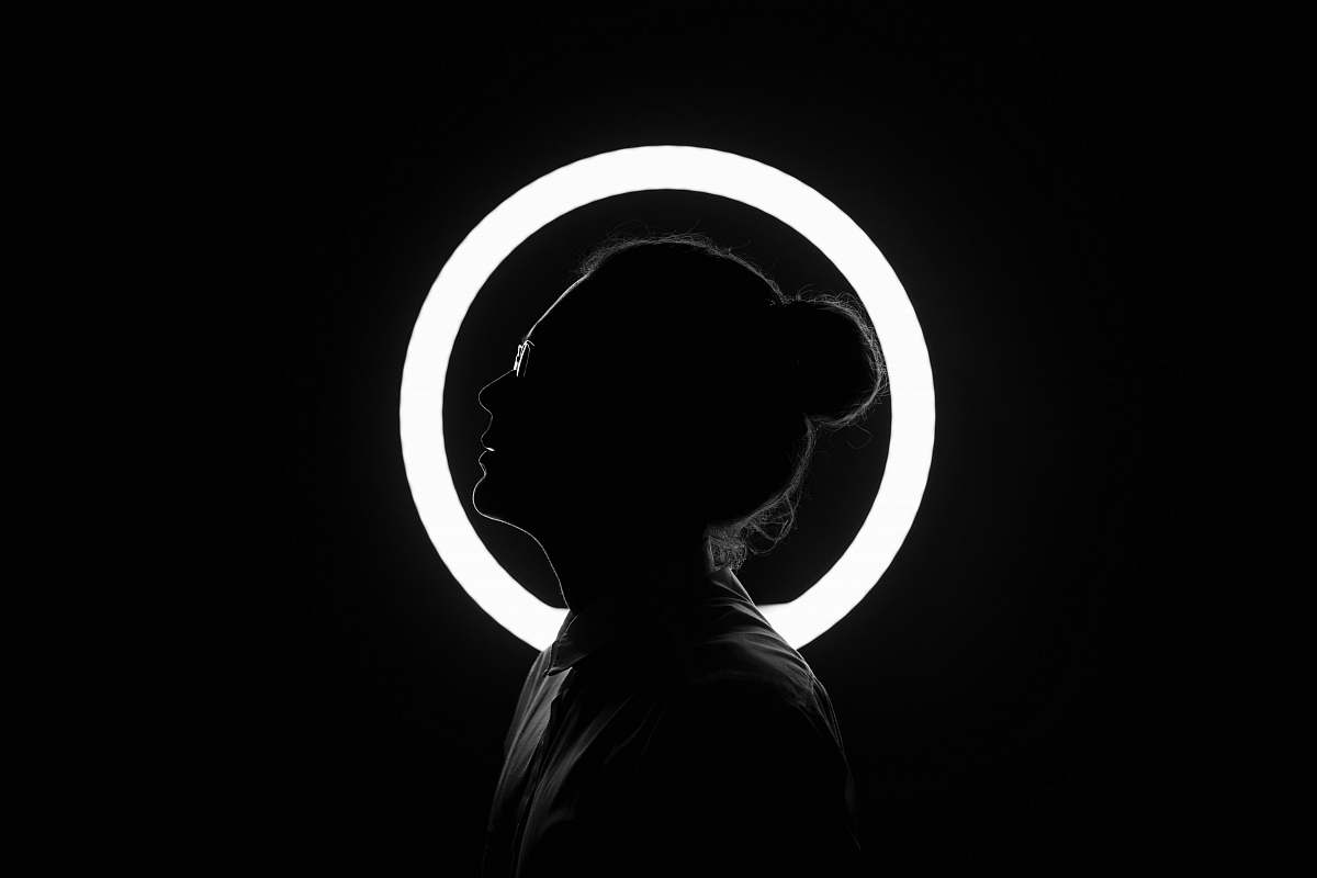 person woman standing beside halo light black-and-white