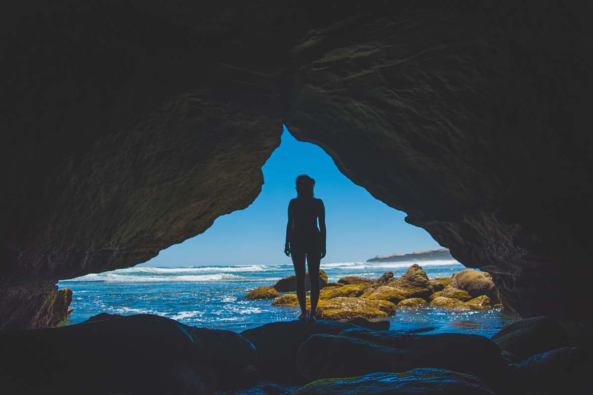 woman woman standing inside cave during daytime cave