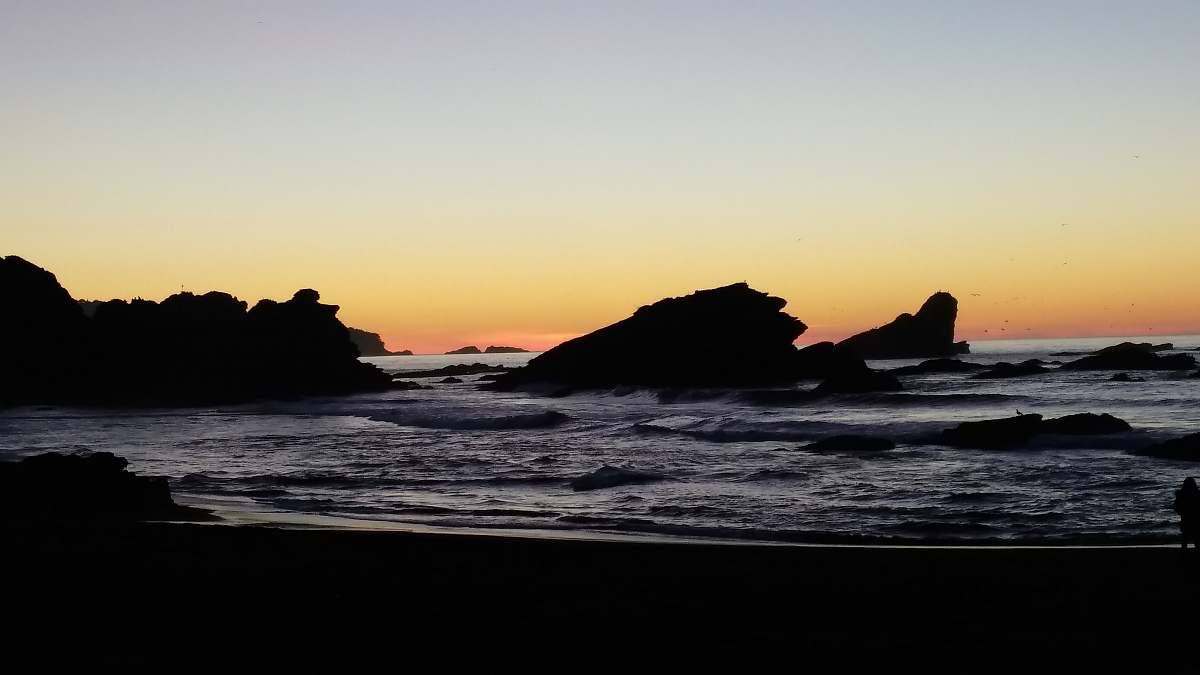 beach rocks covered with body of water during golden hour ocean