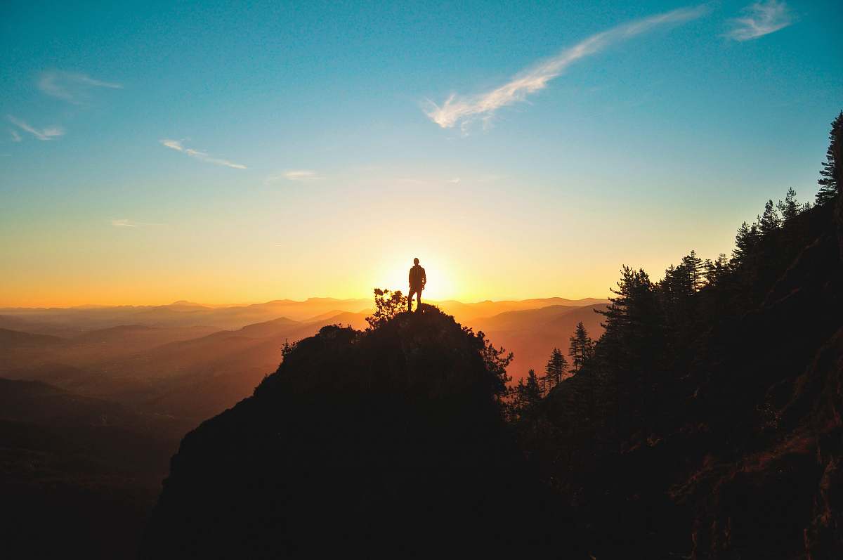 sunset silhouette of man standing on mountain peak sunrise