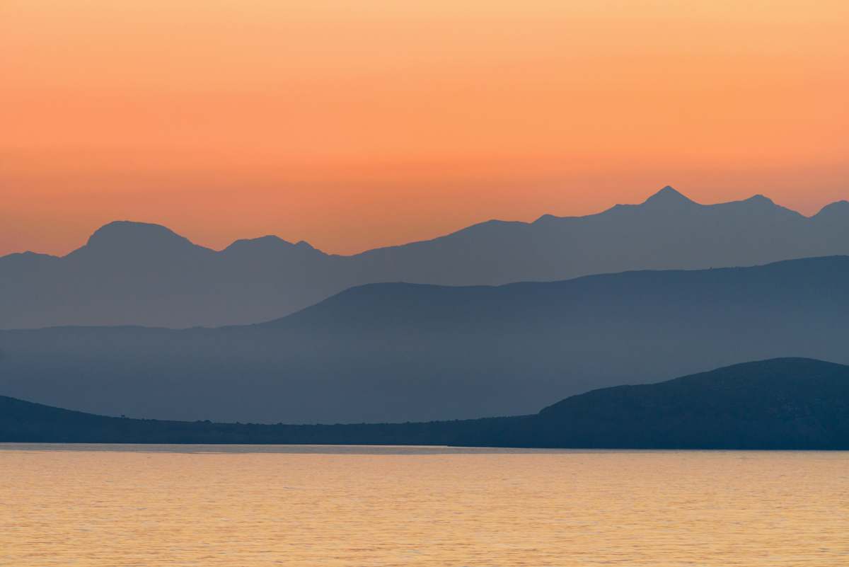 sunset silhouette of mountains near body of water during golden hour greece