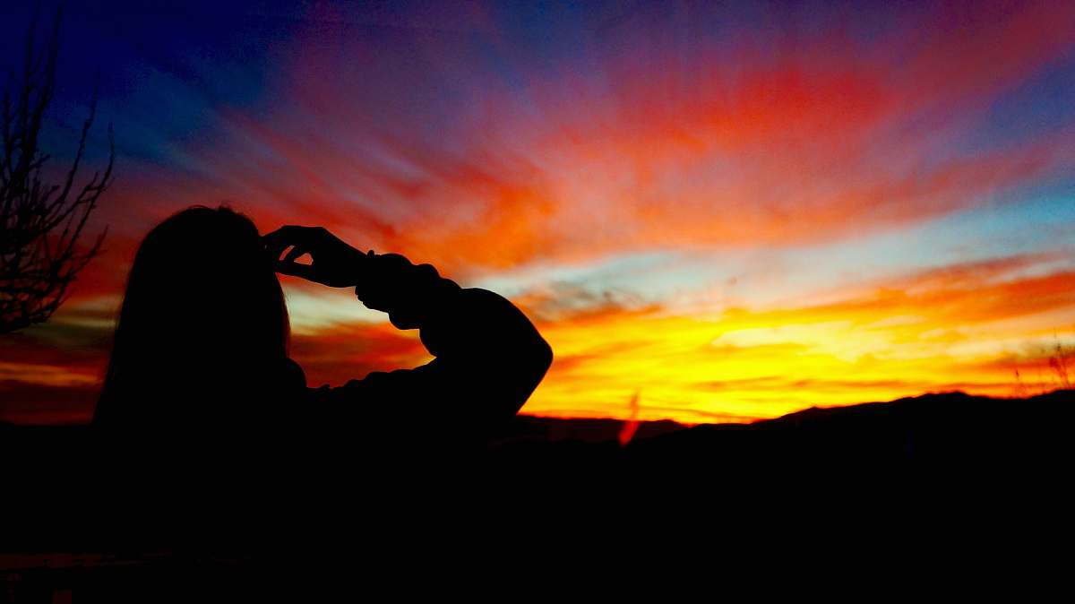 sunset silhouette of person facing mountain during golden hour silhouette