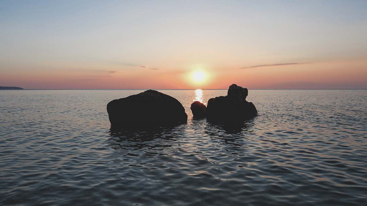 greece silhouette of rocks on body of water during golden hour rocks