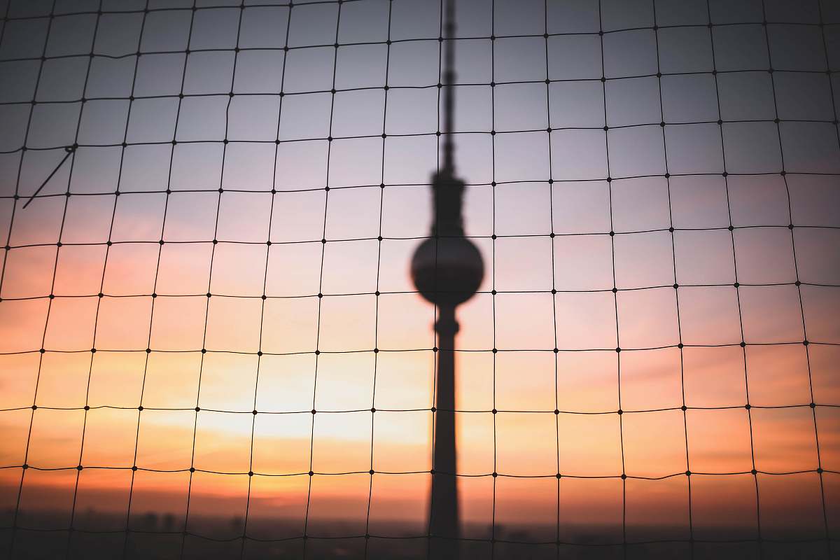 berlin silhouette photo of hanging decor behind chain link fence at golden hour germany