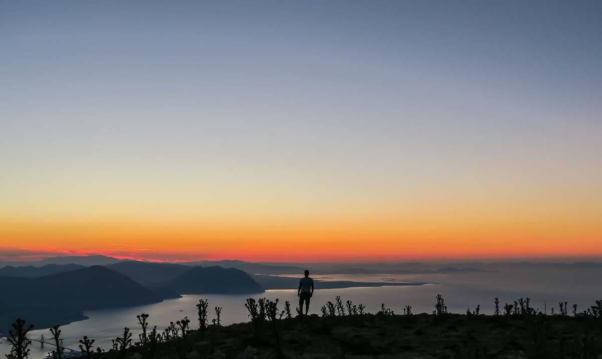 sunrise silhouette photo of man standing on mountain nature