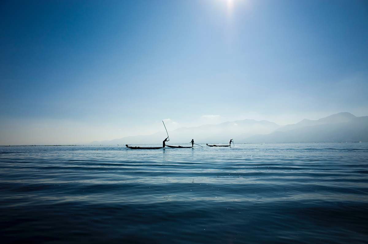 blue calm body water under blue sky fishing