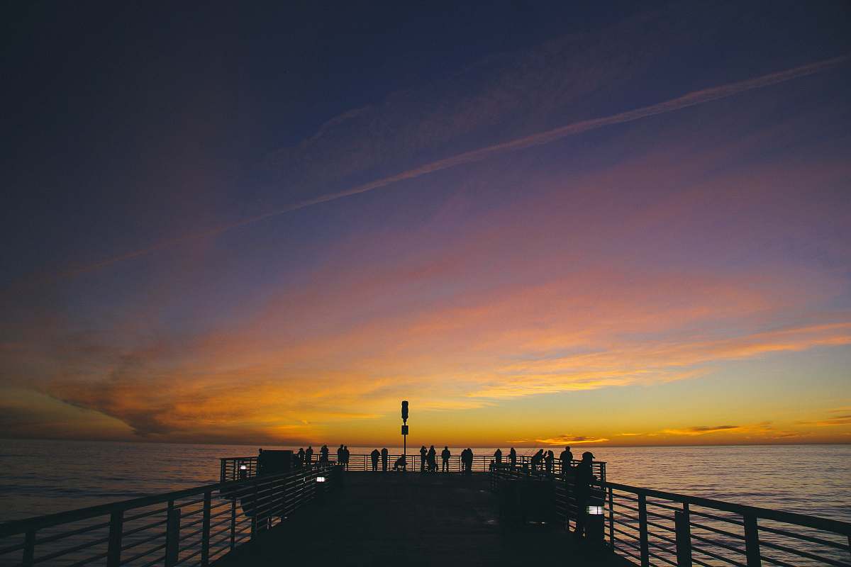 dock silhouette of people on dock near body of water during golden hour pier
