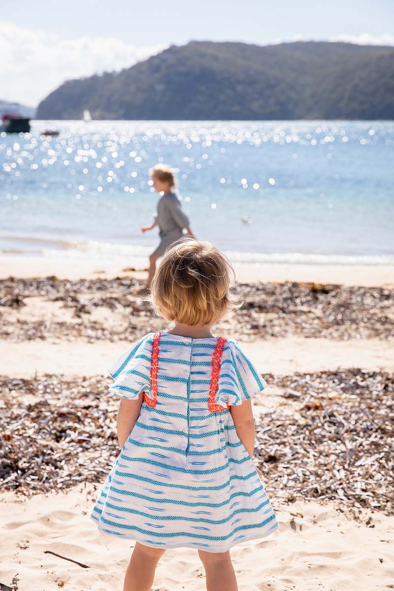 ocean girl wearing white and blue cap-sleeved shirt dress near beach sea
