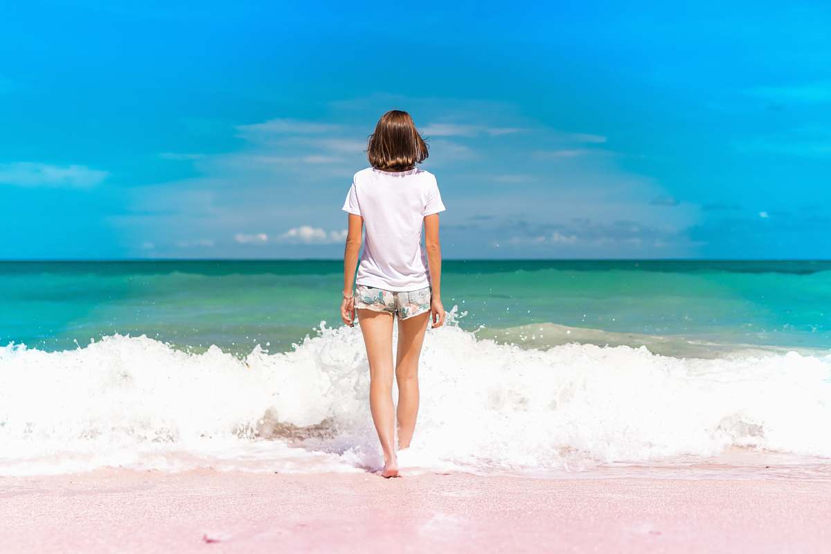 water time lapse photography of woman standing in front of sea waves person
