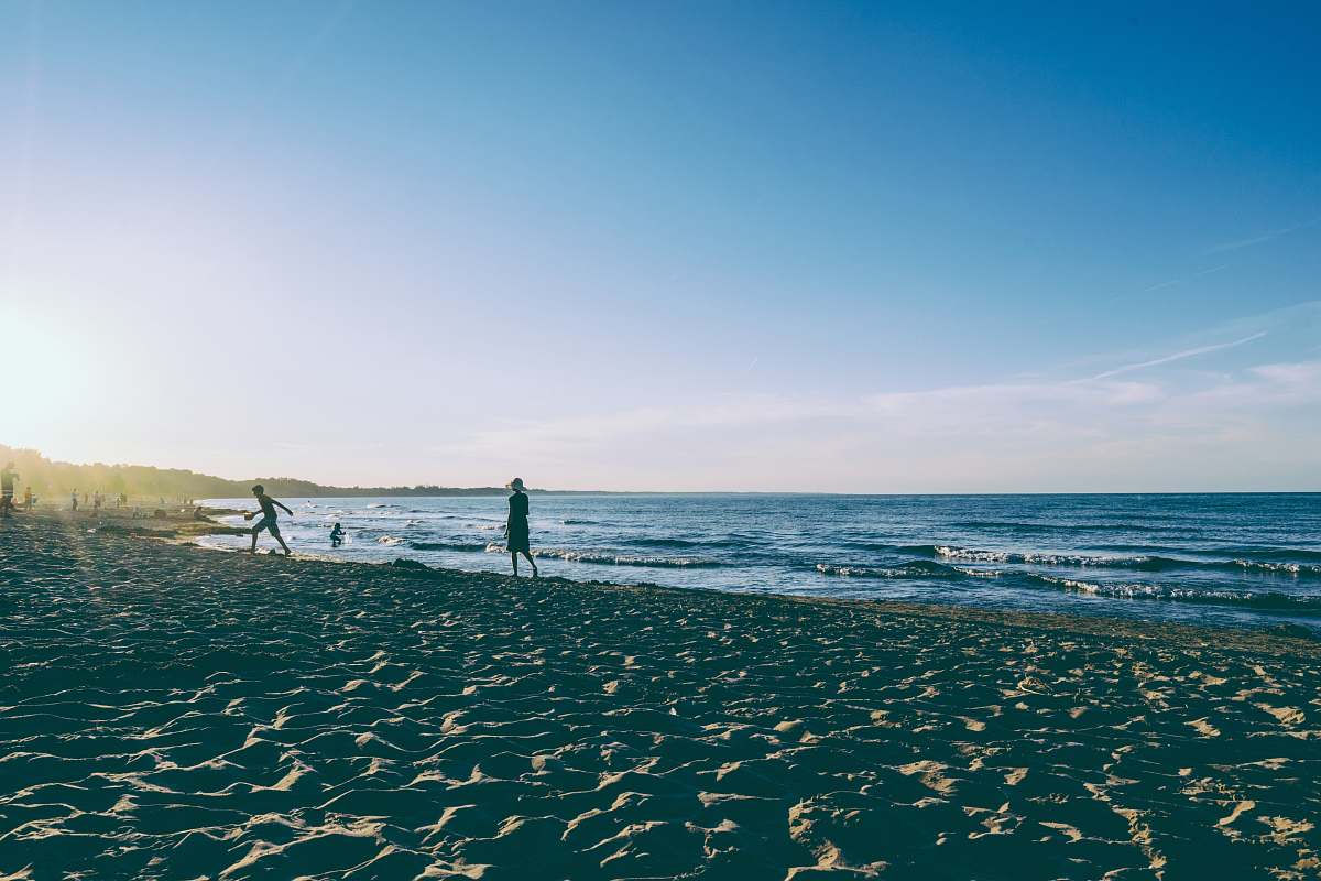 coast two person walking on seashore during daytime ocean