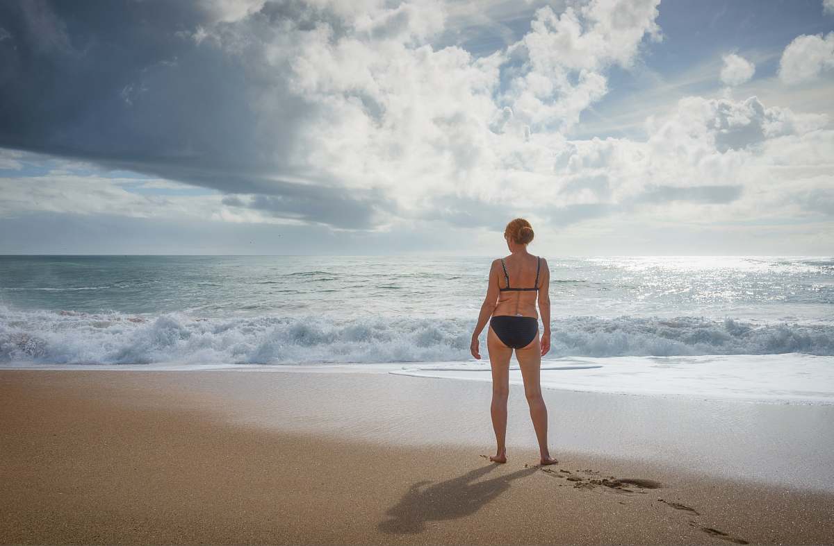 nature woman standing on the seashore facing the ocean sea