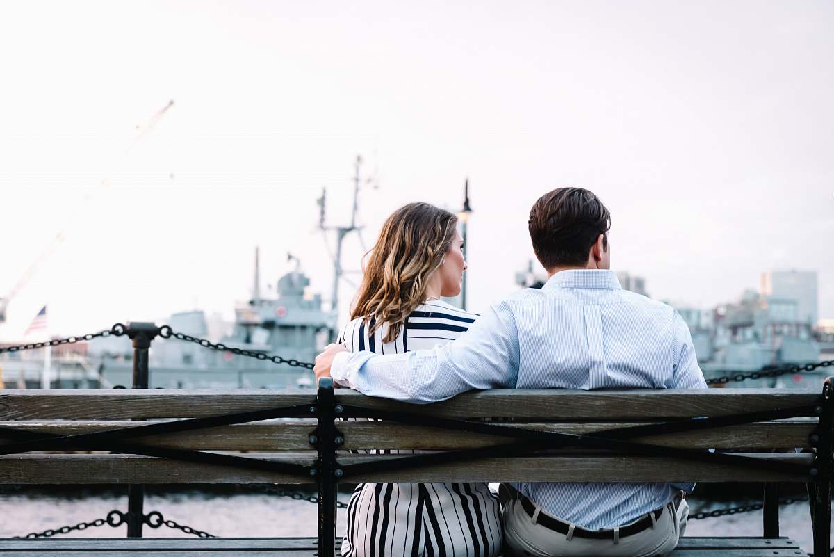 back couple sitting on bench near body of water love