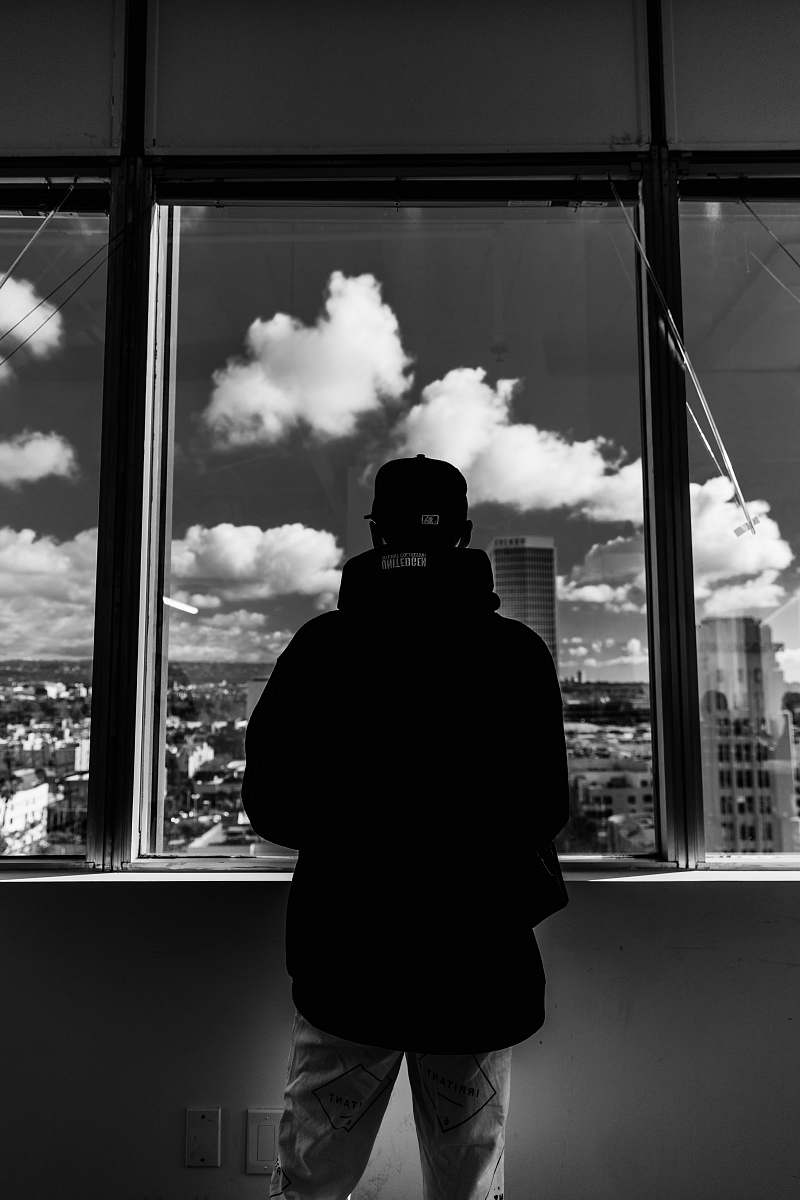 human grayscale photo of man standing near window person
