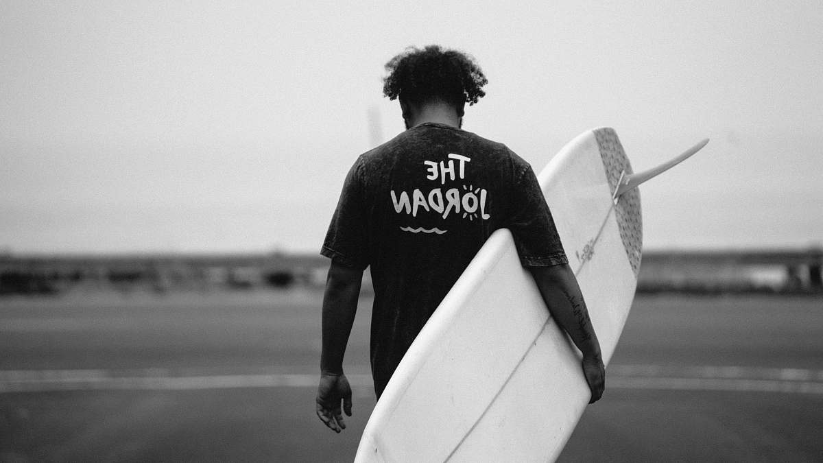 surfboard grayscale photo of man walking holding surfboard surfing
