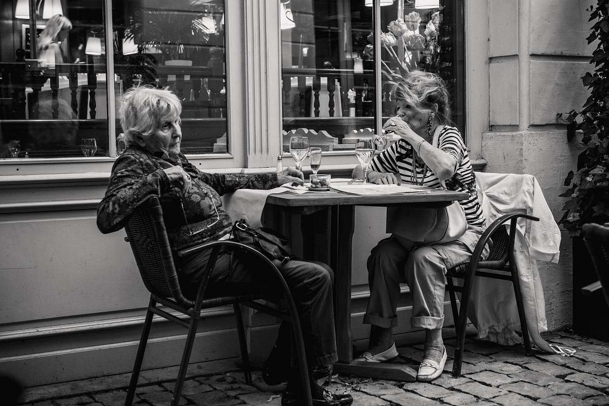 woman grayscale photo of two woman sitting beside the table women