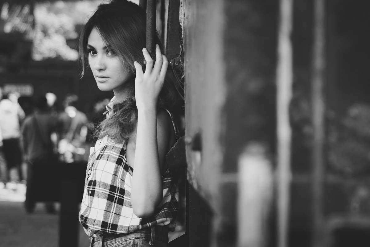human grayscale photo of woman leaning on wall person