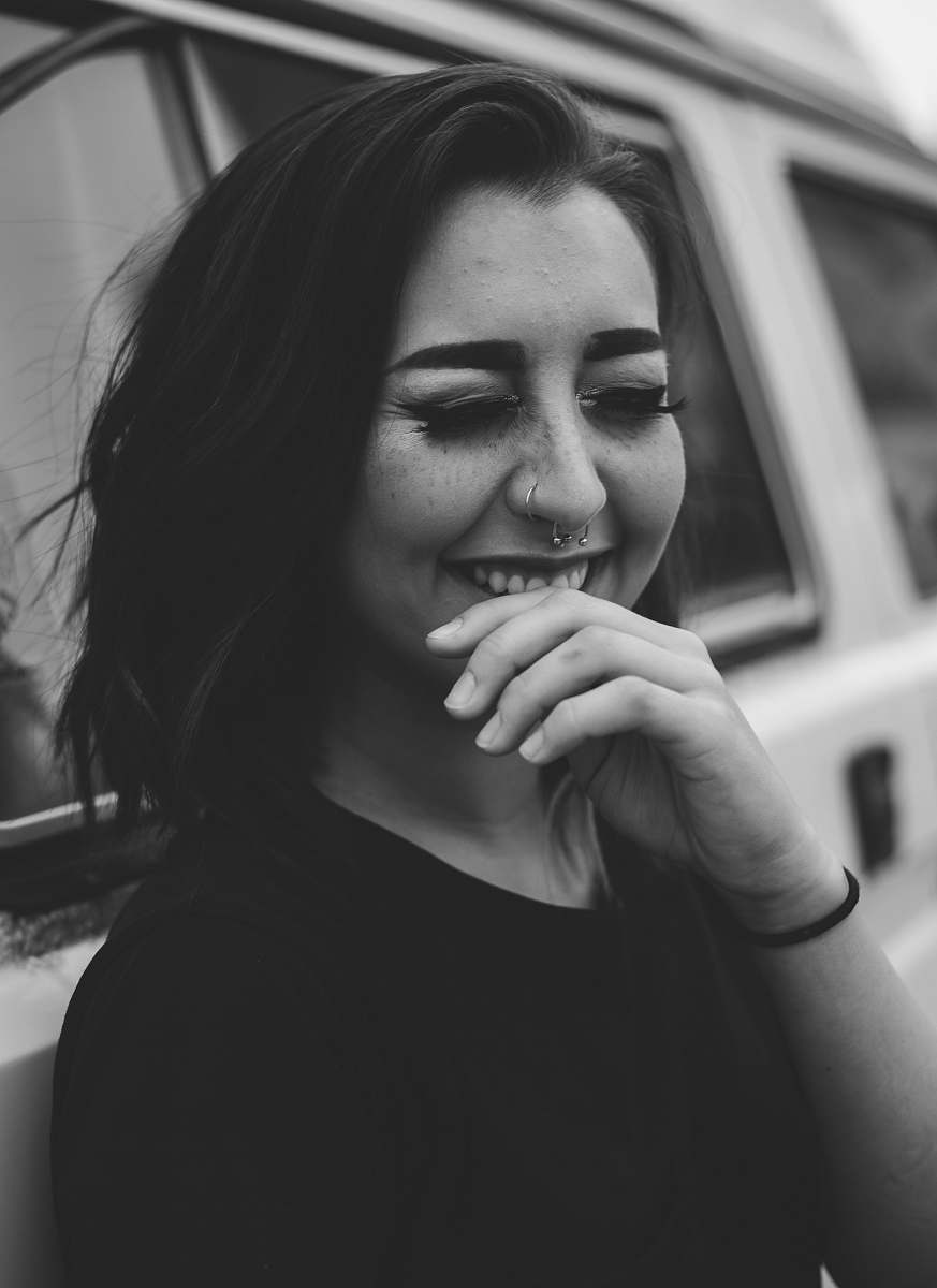 human grayscale photo of woman smiles leaning on car people