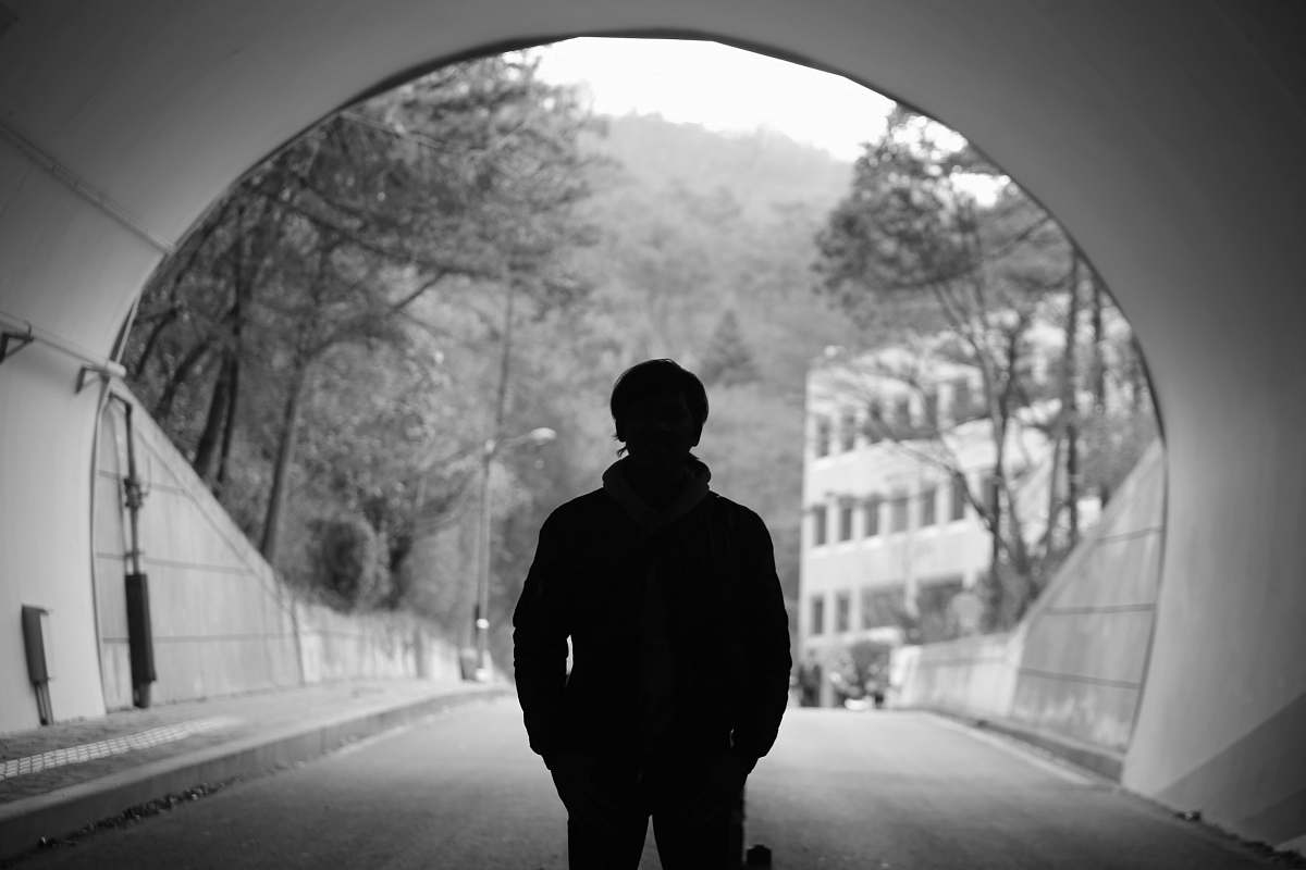 human grayscale photography of man standing in tunnel people