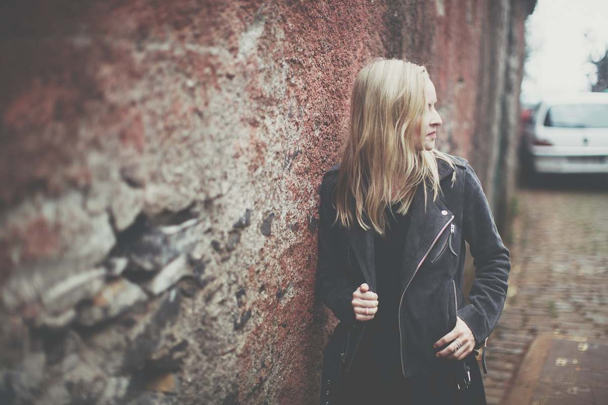 female woman standing beside brown wall during daytime girl