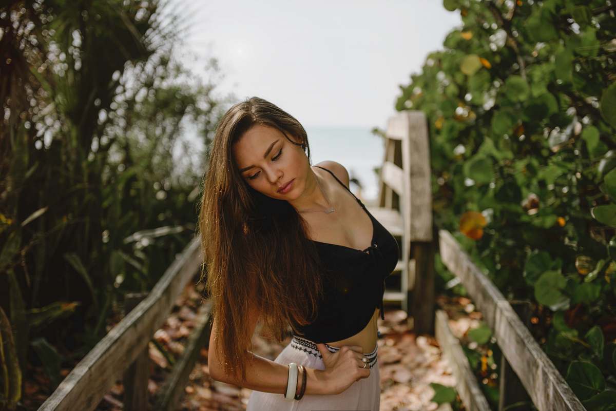 female woman standing on bridge in between trees during daytime woman
