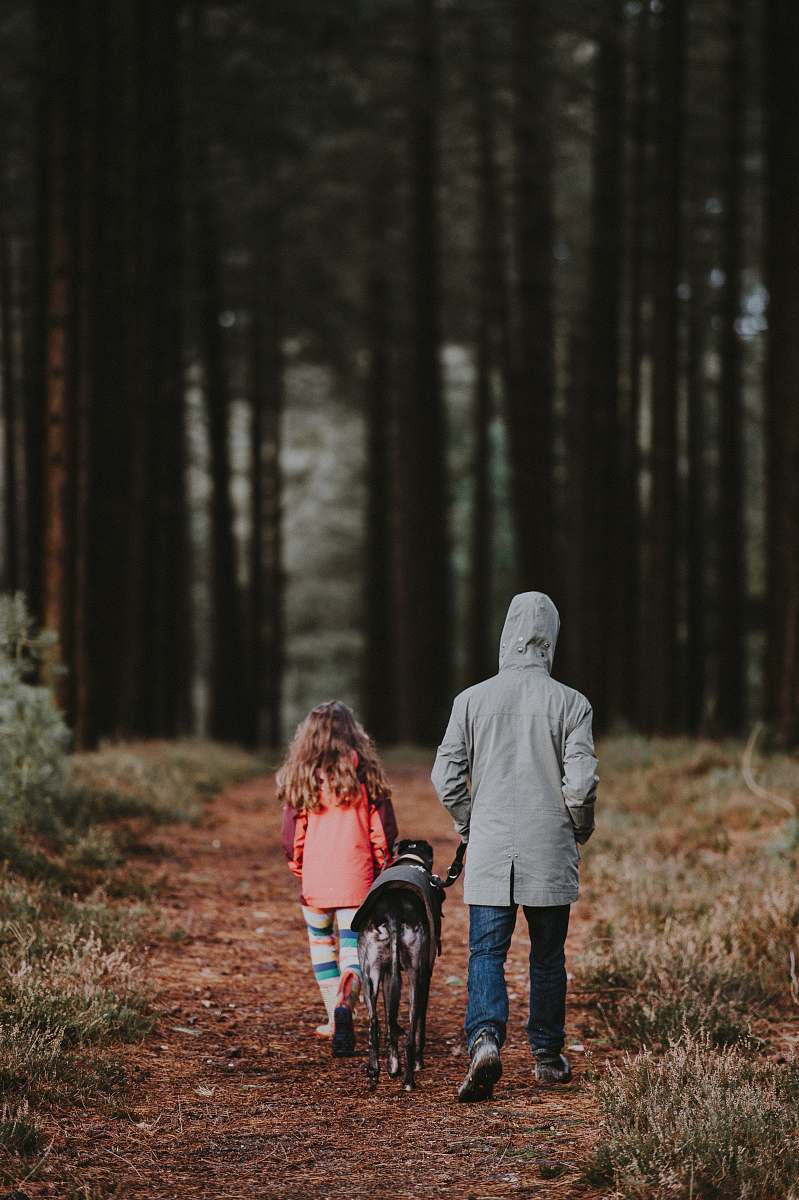 people black dog between man and girl walking person