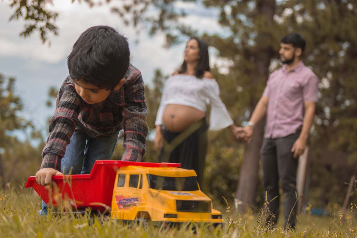 people boy playing red and yellow truck on grass field person