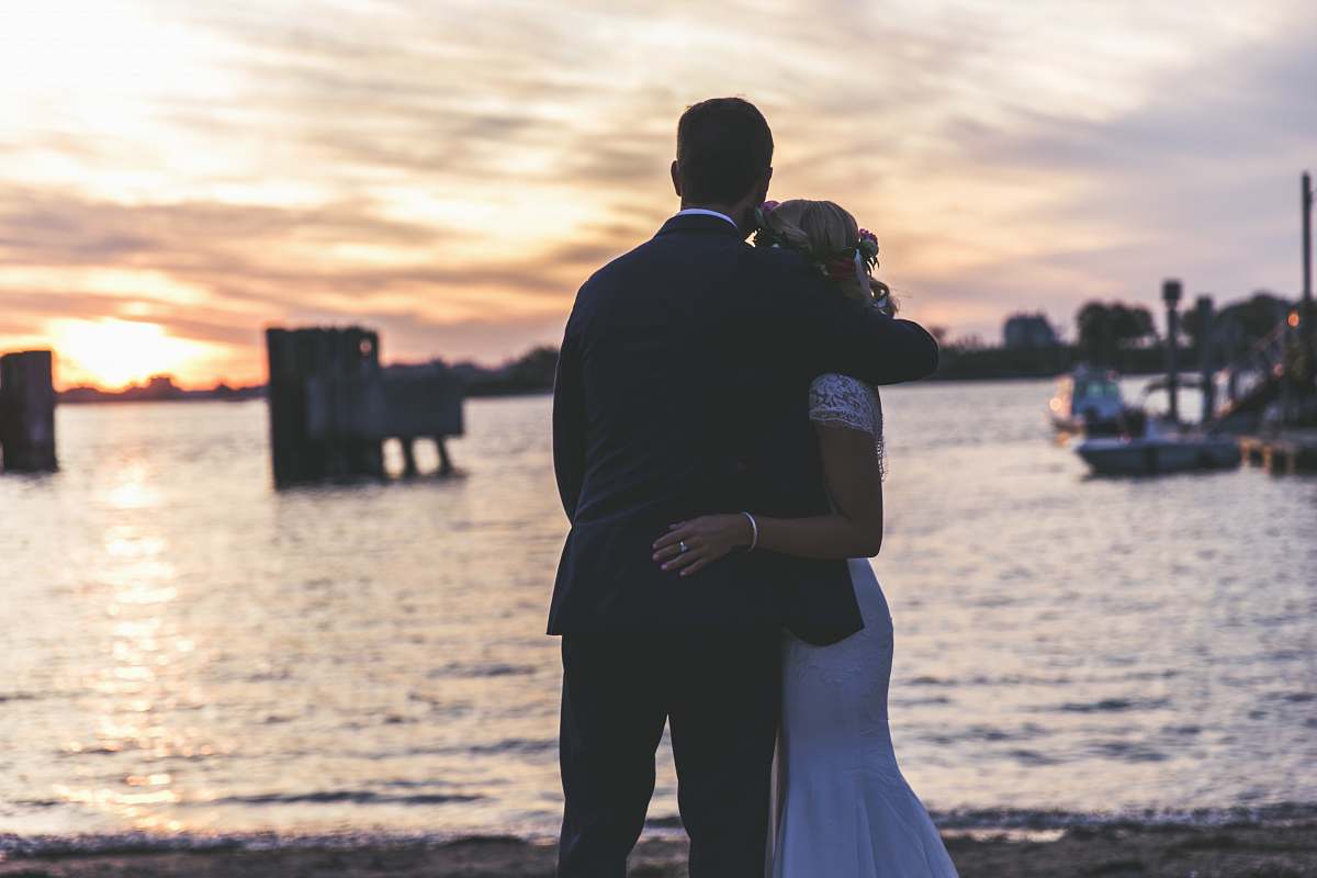 person bride and groom hugging near seashore boat