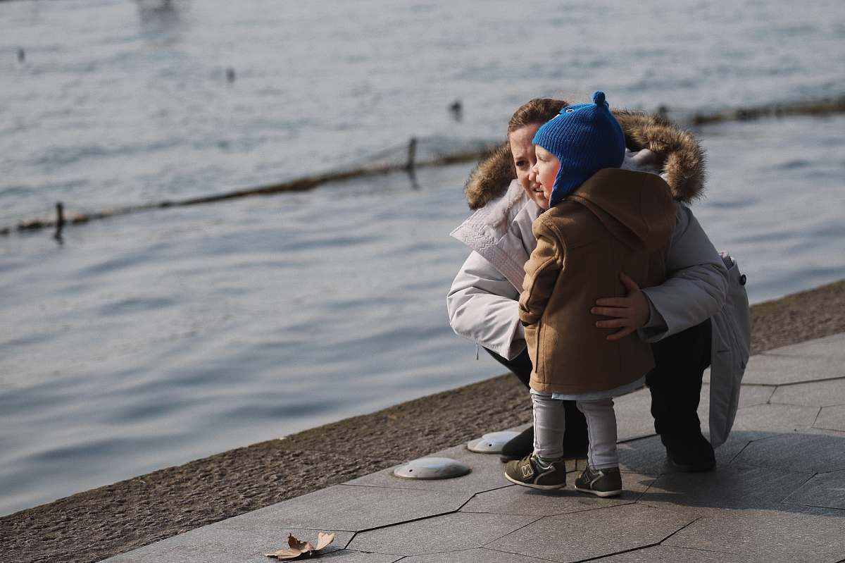 people child standing on concrete bay together with sitting woman person