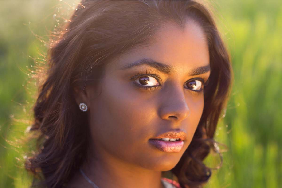 This stunning close-up photograph captures a woman immersed in a vibrant field, illuminated by bright, natural light. The image highlights her expressions and the beauty of her surroundings, making it perfect for various uses such as inspirational content, wellness blogs, or nature-themed projects. It evokes feelings of tranquility and connection with nature, ideal for marketing materials, social media posts, or personal websites.