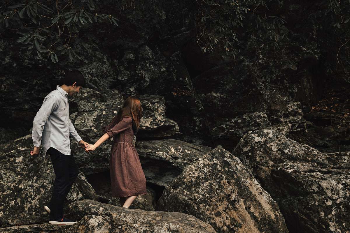 people couple standing on rocky cliff person