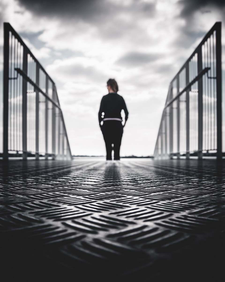 person grayscale photo of woman in between gray metal railings black-and-white