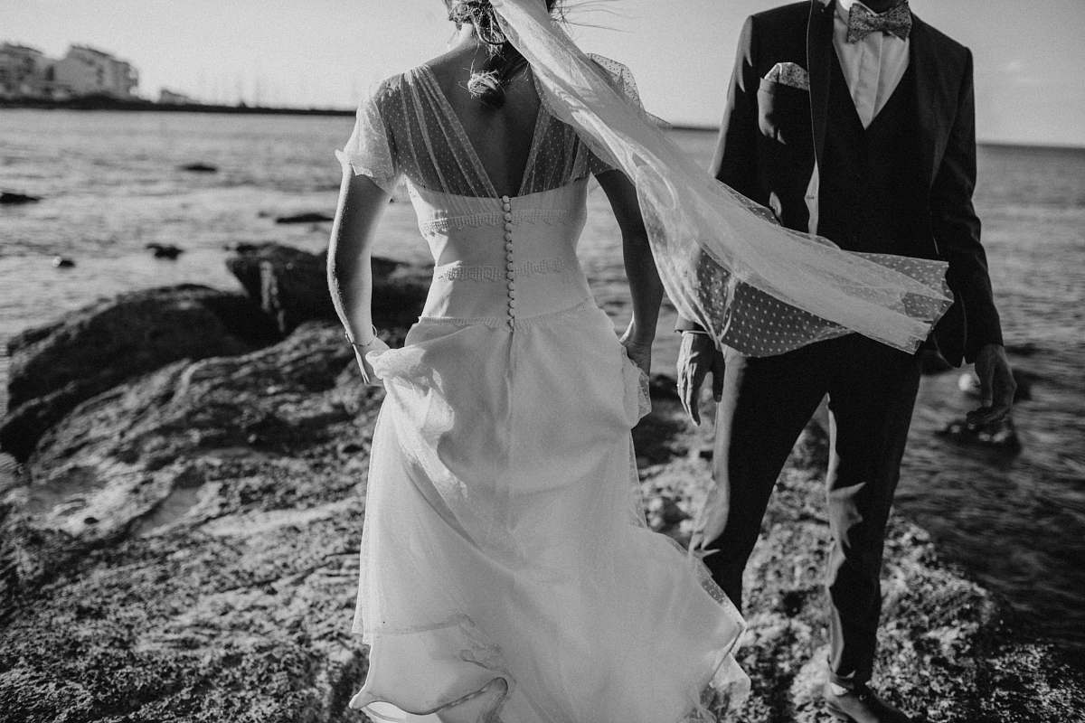 person grayscale photography of groom and bridge on seashore during daytime black-and-white