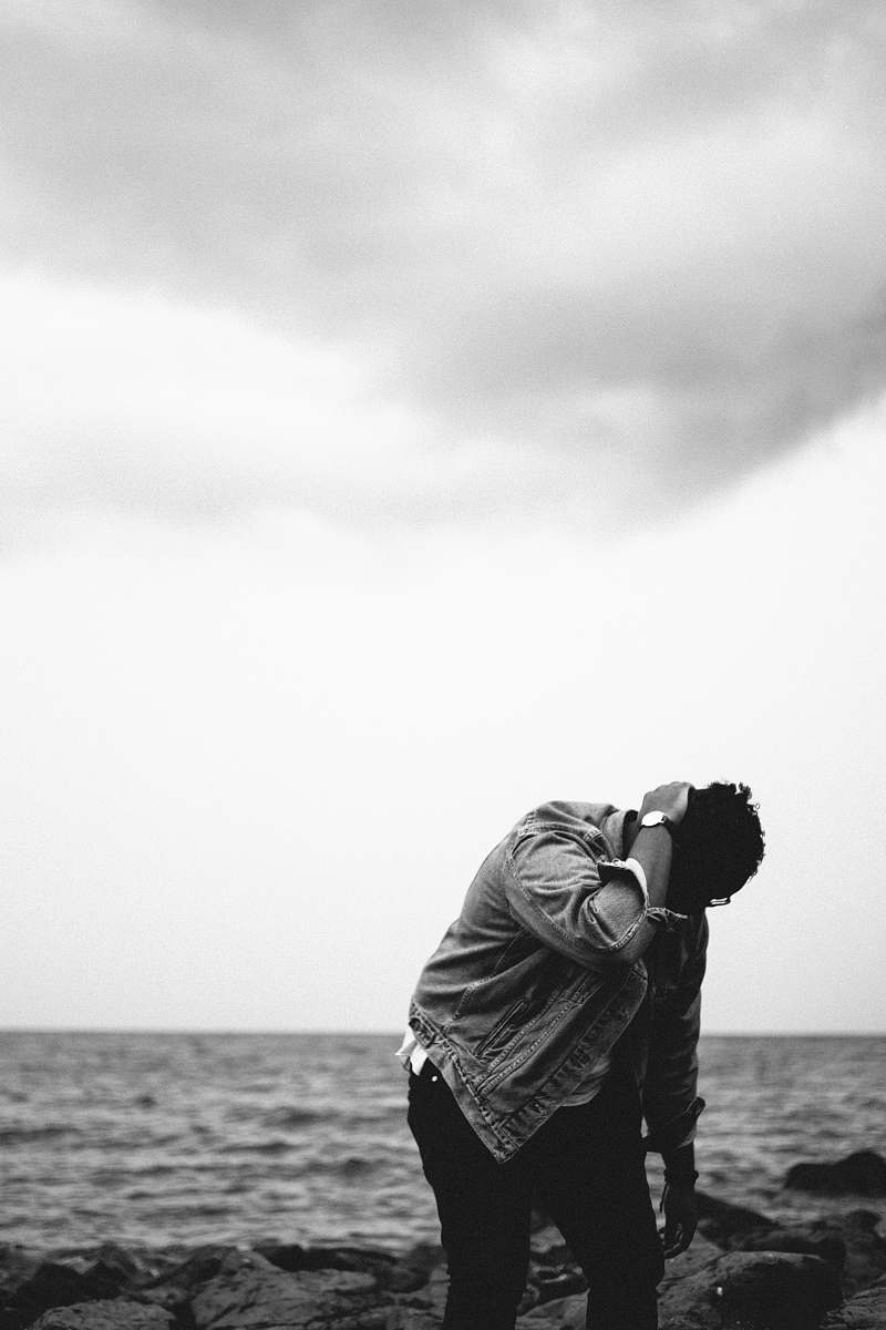 person grayscale photography of person looking down at rocks black-and-white