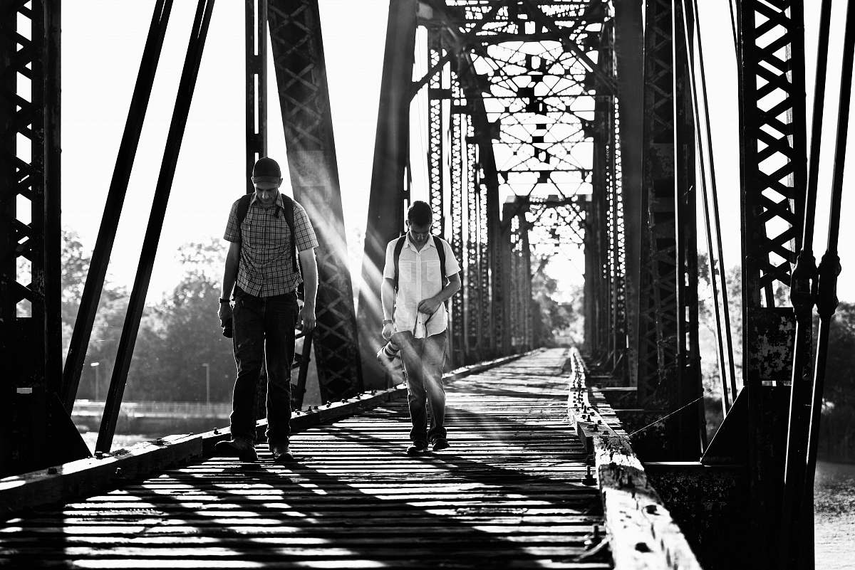 person grayscale photography of two men on bridge black-and-white