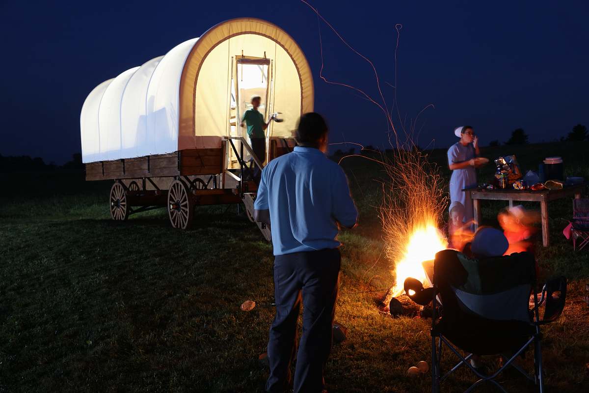 people group of people surrounding bonfire behind carriage person