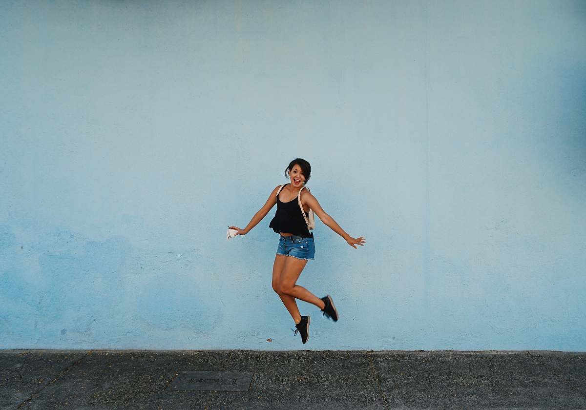 people jumping woman on gray ground under white cloud blue skies person