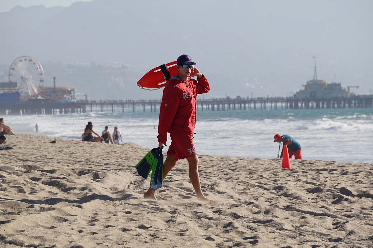 beach lifeguard walking in a sand shore ferris wheel