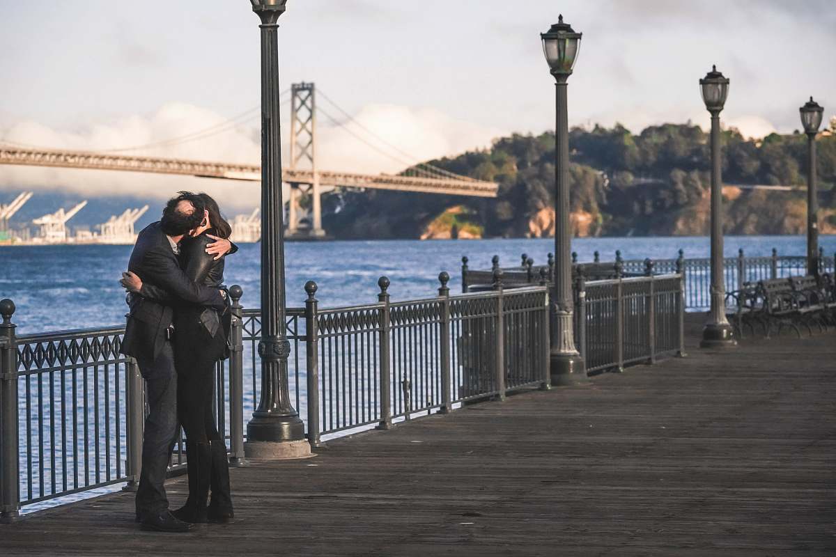 people man and woman kissing beside metal rail guard person