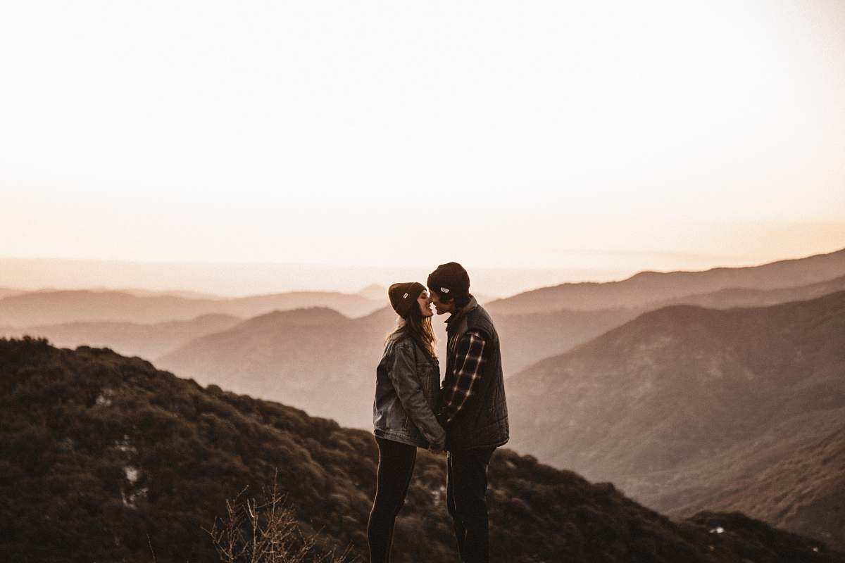 people man and woman kissing on mountain during daytime person