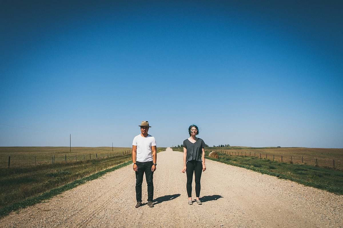 people man and woman standing on road between grass fields during daytime road