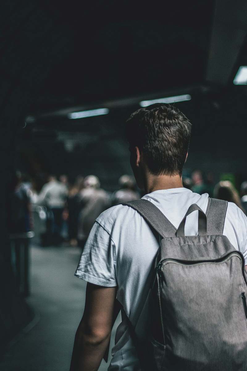 person man carrying backpack standing people